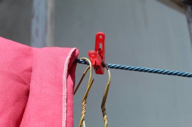 Pembe elbiseler sıcak bir günde çamaşır ipiyle ve askılarla kurutulur.