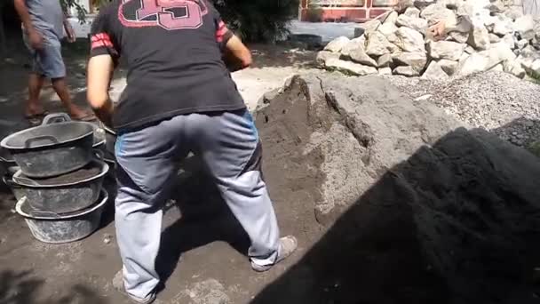 模糊的视野 工人们正在把手推车推成混凝土 工人们正在把混凝土从水泥搅拌机倒入手推车 使建筑工地上的工人变得模糊不清 — 图库视频影像