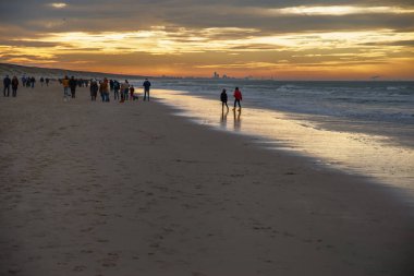 1 Ocak 2022, Katwijk aan Zee, Hollanda plajda yürüyen insanları rahatlattı ve gün batımının altında Sheveningen Peer