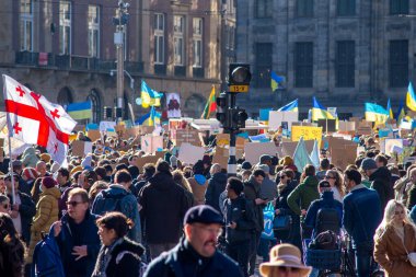 27 Şubat 2022, Baraj Meydanı, Amsterdam, Hollanda Ukrayna 'daki savaşa karşı barışçıl protesto ellerinde Ukrayna bayrakları, sarı ve mavi balonlar ve çeşitli mesajlarla pankartlar var.