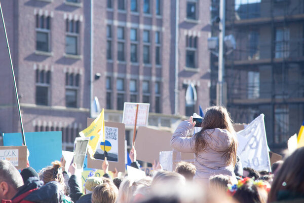 27 февраля 2022 года, площадь Дам, Амстердам, Нидерланды, мирный протест против войны на Украине с флагами Украины, жёлтыми и синими воздушными шарами и табличками с различными посланиями