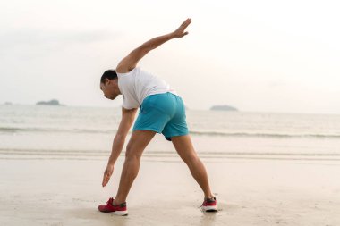 Healthy lifestyle. asian sportman doing sports exercises at the beac
