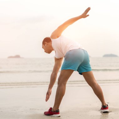 Healthy lifestyle. asian sportman doing sports exercises at the beac