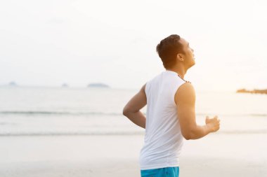 asian sport man running along seaside. running on beach with healthy toned legs body, Hamstring muscles, knee joint health active lifestyle panoramic banner background. the beach runners working out  beach