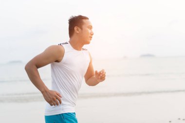 asian sport man running along seaside. running on beach with healthy toned legs body, Hamstring muscles, knee joint health active lifestyle panoramic banner background. the beach runners working out  beach
