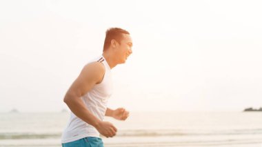 asian sport man running along seaside. running on beach with healthy toned legs body, Hamstring muscles, knee joint health active lifestyle panoramic banner background. the beach runners working out  beach