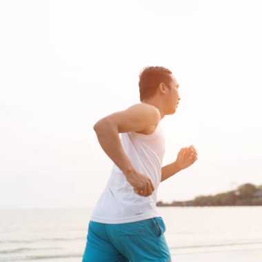 asian sport man running along seaside. running on beach with healthy toned legs body, Hamstring muscles, knee joint health active lifestyle panoramic banner background. the beach runners working out  beach