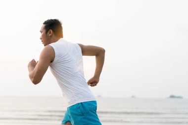 asian sport man running along seaside. running on beach with healthy toned legs body, Hamstring muscles, knee joint health active lifestyle panoramic banner background. the beach runners working out  beach