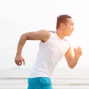 asian sport man running along seaside. running on beach with healthy toned legs body, Hamstring muscles, knee joint health active lifestyle panoramic banner background. the beach runners working out  beach