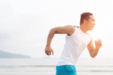 asian sport man running along seaside. running on beach with healthy toned legs body, Hamstring muscles, knee joint health active lifestyle panoramic banner background. the beach runners working out  beach
