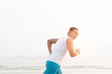 asian sport man running along seaside. running on beach with healthy toned legs body, Hamstring muscles, knee joint health active lifestyle panoramic banner background. the beach runners working out  beach