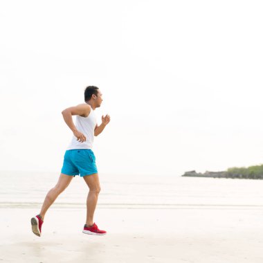 asian sport man running along seaside. running on beach with healthy toned legs body, Hamstring muscles, knee joint health active lifestyle panoramic banner background. the beach runners working out  beach