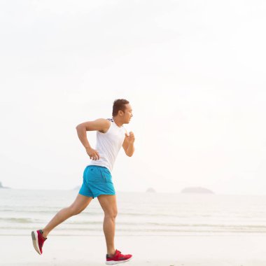 asian sport man running along seaside. running on beach with healthy toned legs body, Hamstring muscles, knee joint health active lifestyle panoramic banner background. the beach runners working out  beach