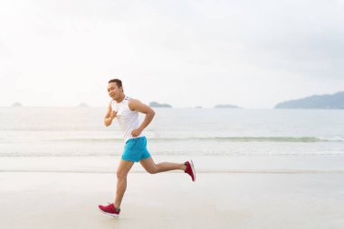 asian sport man running along seaside. running on beach with healthy toned legs body, Hamstring muscles, knee joint health active lifestyle panoramic banner background. the beach runners working out  beach