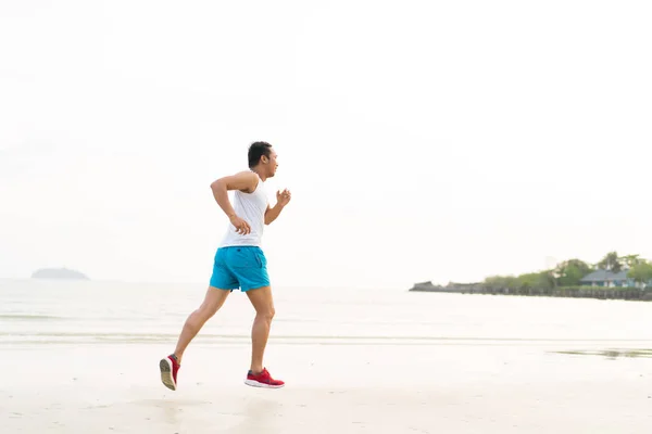 asian sport man running along seaside. running on beach with healthy toned legs body, Hamstring muscles, knee joint health active lifestyle panoramic banner background. the beach runners working out  beach