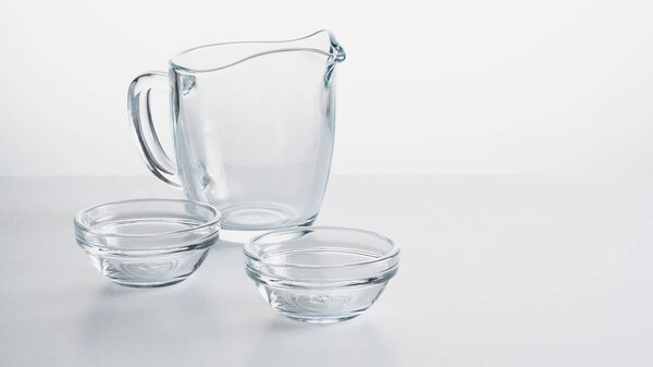 empty glass jug and two glass cups on a white background