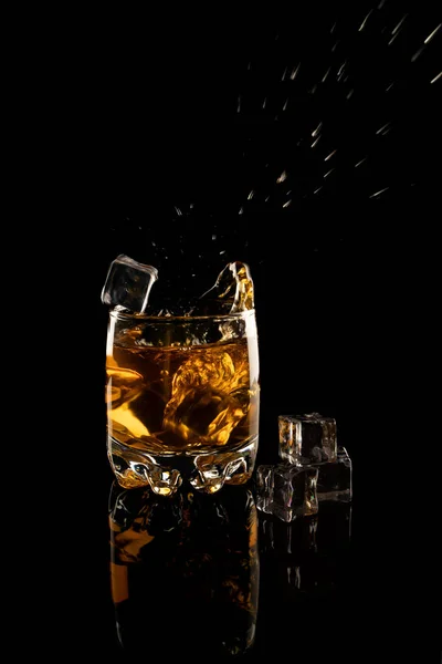 一杯威士忌 冰块飘落并溅在黑色的背景上 — 图库照片