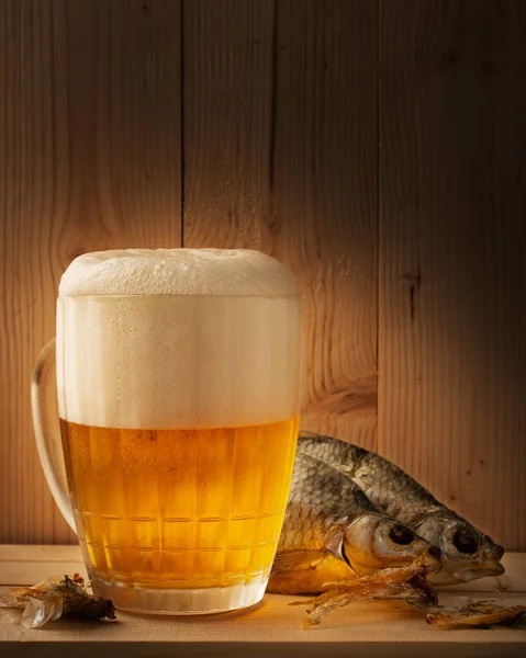 a mug of light beer with dried fish on a wooden table