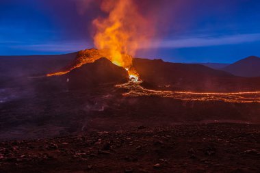 İzlanda 'da volkanik patlama. Geceleri Fagradalsfjall volkanından mavi gökyüzüne kadar uzanan krater sıvı lav ile. GeoPark 'taki Reykjanes yarımadasında volkan..