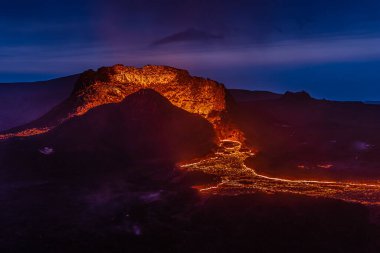 İzlanda 'daki volkanik patlamanın oluşturduğu kraterden gelen lav akışı. Fagradalsfjall volkanından geceleri mavi gökyüzüne uzanan krater. GeoPark 'taki Reykjanes yarımadasında volkan.