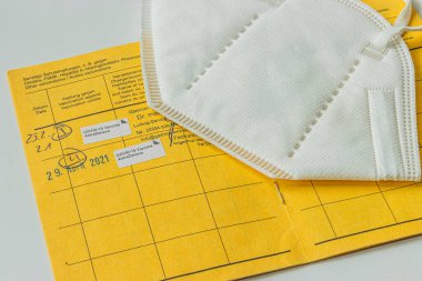 Sarı uluslararası aşı kartı ve beyaz yüz maskesi. Coronavirus 'a karşı yapılan çifte aşının kaydı. Dünya Sağlık Örgütü 'nün sarı aşı kayıtlarından bir sayfa.