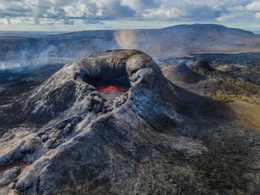 İzlanda 'nın Reykjanes Yarımadası' nda aktif volkan. Sıvı magmalı volkanik krater. Patlamadan hemen önce kraterin ortasında sıvı lav var. Gün ışığında kırsal tepeler ve dağlar.
