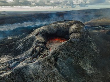 Ağzında kırmızı lavla kraterin içine bak. İzlanda 'da manzara. Gündüzleri Reykjanes Yarımadası 'nda volkanik krater. Patlamadan önce krater. Krater ve buhar etrafında koyu soğutulmuş lav.