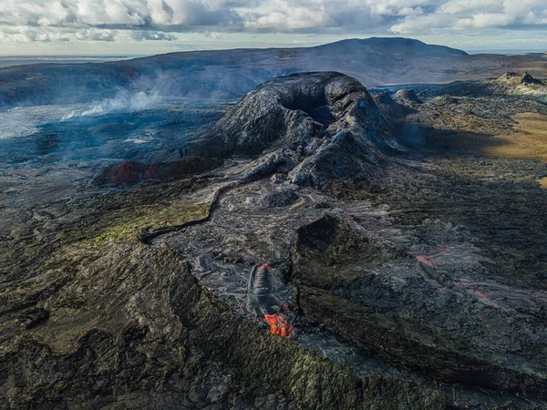 İzlanda 'nın Reykjanes Yarımadası' ndaki aktif kraterin en üst görüntüsü. Kraterin etrafında buhar sütunlarıyla serinletilmiş lav akışının manzarası. yeşil, siyah, gri ve kırmızı lav kayaları
