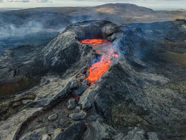 Patlamanın başlangıcında güçlü lav akışının olduğu aktif bir volkanın kraterine bakın. İzlanda 'nın Reykjanes Yarımadası' ndaki manzara. Koyu magma kayaları volkanik kraterin etrafında soğudu.