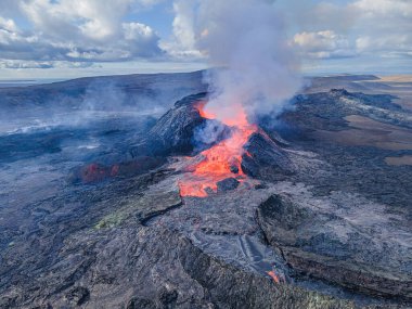 İzlanda 'daki bir volkandan çıkan kızgın lavlar. Yukarıdan Reykjanes Yarımadası 'nın kraterine bakın. Kraterin yanında buhar ve duman var. Kraterlerin etrafında soğutulmuş magma. Gündüz gökyüzünde bulutlar