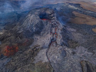 Gündüzleri Reykjanes yarımadasındaki aktif volkanın en üst görüntüsü. İzlanda 'da volkanik krater. Kraterin etrafında küçük bir duman bulutu ile kara magma kayası. Patlamadan önce kraterde küçük lav akışı olur..
