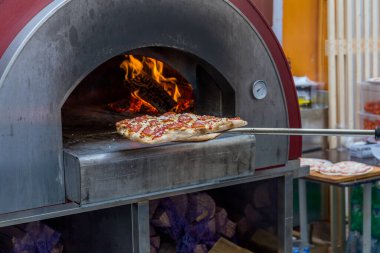 Sokakta yanan bir fırında İtalyan pizzası pişirmek.