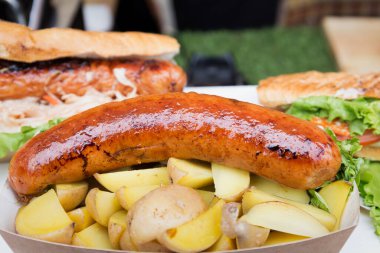 Kızarmış sosis ve baharatlı fırında patates büyük bir kızartma tavasında yatıyor. Sokak yemeği. Yatay resim.