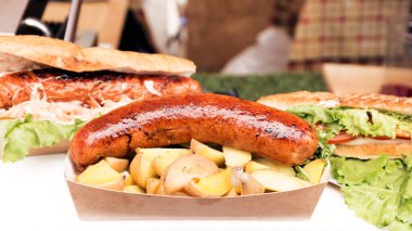 Kızarmış sosis ve baharatlı fırında patates büyük bir kızartma tavasında yatıyor. Sokak yemeği. Yatay resim.