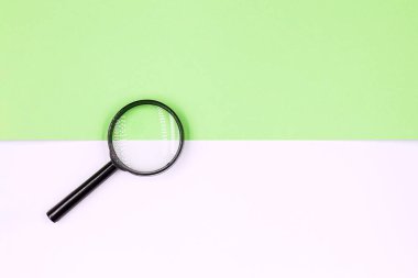 Büyüteç beyaz-yeşil arka planda duruyor. Minimum geometrik şekil ve çizgiler. Boşluğu kopyala.