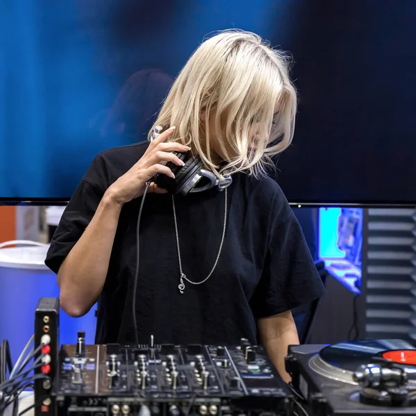 Moskova, Rusya, 12 Nisan 2019: Genç sarışın bir DJ kız vinil bir pikapta müzik çalıyor ve kulaklıkla yeni bir parça dinliyor.
