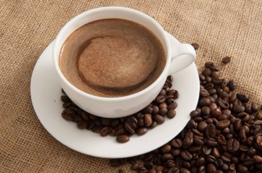 Kahveli ve buharlı fincan, arka planda çuval bezi