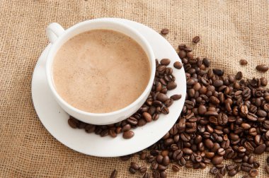 Burlap arka planda kahve çekirdekleri ile kahve Fincan