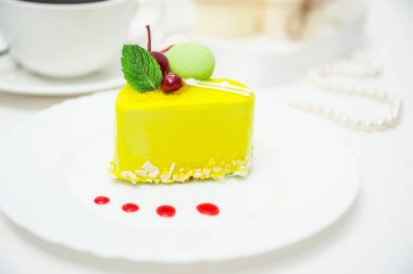 kirazlı limon sarısı kalp pastası ve beyaz arka planda krema.