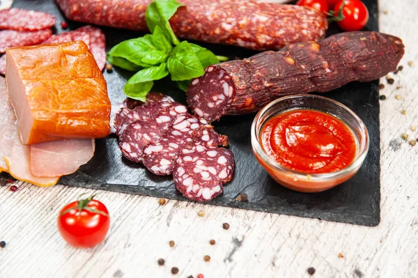 Salsicha fumada, carne, bacon com manjericão e tomate cereja — Fotografia de Stock