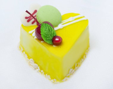 kirazlı limon sarısı kalp pastası ve beyaz arka planda krema.