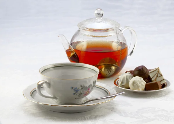 Cup on a saucer, teapot and chocolates — Stock Photo, Image