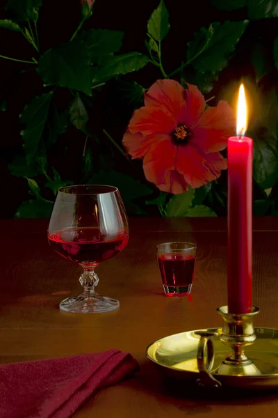 Ein Glas Rotwein, ein kleines Glas Schnaps und eine brennende Kerze — Stockfoto