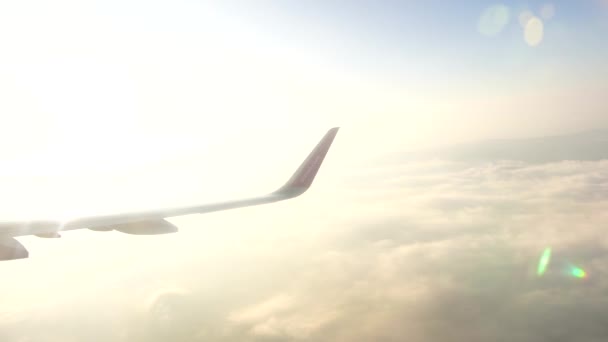 Vleugel van een vliegtuig dat in fel zonlicht boven de wolken vliegt — Stockvideo