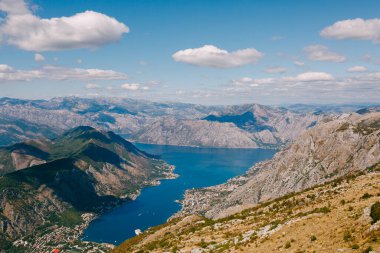 Kotor Körfezi 'nin masmavi sularının üzerinde beyaz bulutlar olan mavi gökyüzü. Lovcen Dağı