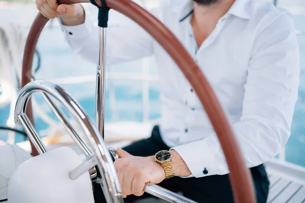 Hands of the man in white shirt sitting at the helm on a yacht sailing in the middle of the sea, close-up — Stock Photo, Image