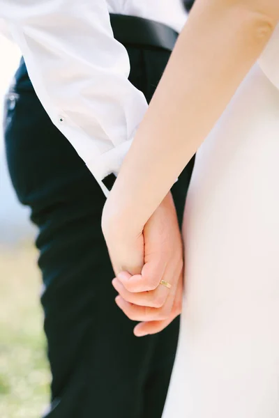白いシャツと黒いズボンの新郎の手は白いドレスで花嫁の手を保持しています。閉鎖 — ストック写真