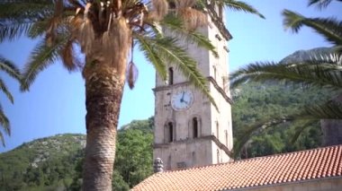 Aziz Niklas Kilisesi 'nin çan kulesinin arka planında palmiye ağacı var. Perast, Karadağ