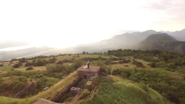 Recém-casados abraçam-se enquanto estão em pé nas fortificações do forte Gorazda no Monte Lovcen — Vídeo de Stock