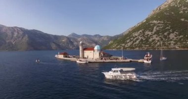 Beyaz yat Gospa od Skrpjela adasının yanından geçiyor.